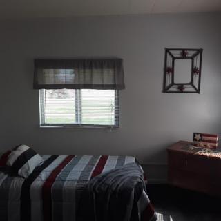 A cozy bedroom featuring a neatly made bed, a desk, and natural light coming through the window.