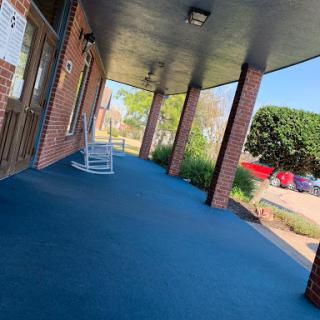 A serene porch area featuring a rocking chair and well-maintained surroundings.