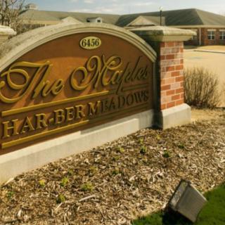 A neighborhood entrance sign for 'The Maples at Harbern Meadows' surrounded by landscaping.