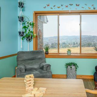 A cozy living room with an armchair, a window overlooking a scenic view, and a Jenga game on the table.