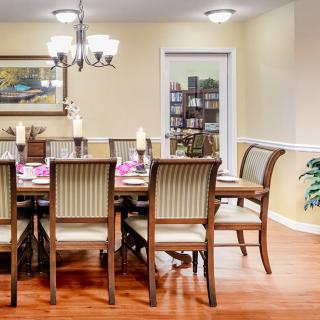 A beautifully decorated dining room with a long wooden table and chairs, adorned with candles and elegant decor.