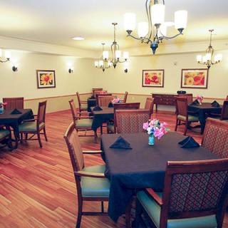 A cozy dining room with neatly arranged tables and elegant chandeliers.