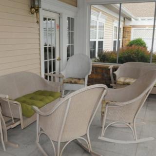 A cozy indoor patio with wicker furniture and large windows.