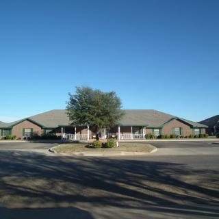 A suburban residential building with a tree in front under a clear blue sky.