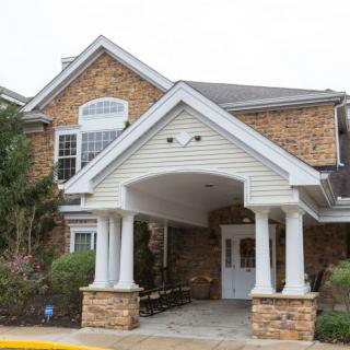 A brick building with a covered entrance and white columns.