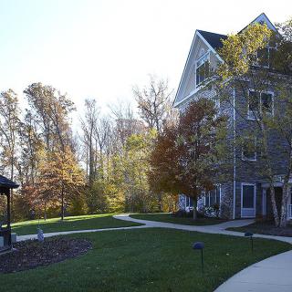 A picturesque view of a building surrounded by trees and a well-maintained lawn.