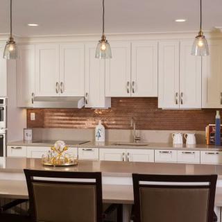 A modern kitchen with white cabinets and stylish pendant lighting.