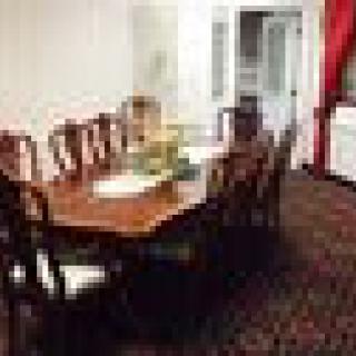 A dining room with a large wooden table and matching chairs, decorated with a centerpiece on the table.