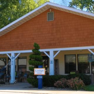 A small wooden building with a storefront and a sign, surrounded by trees.