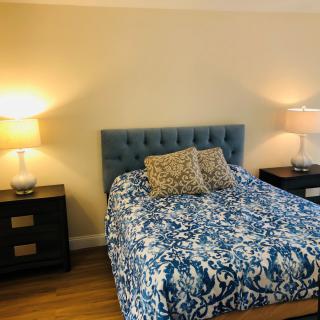 A cozy bedroom with a blue-patterned bedspread and matching nightstands with lamps.