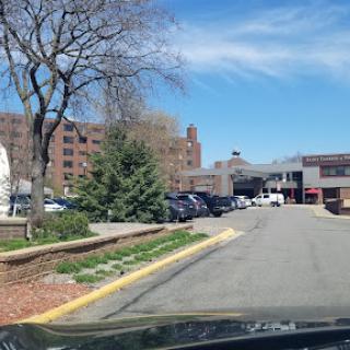 A view of a parking area with buildings and trees on a sunny day.