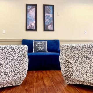 A cozy living room with patterned chairs, a blue couch, and framed artwork on the wall.