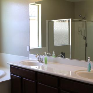 A modern bathroom with a double sink vanity and glass-enclosed shower.