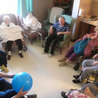 A group of elderly individuals participating in a ball game at a nursing home.