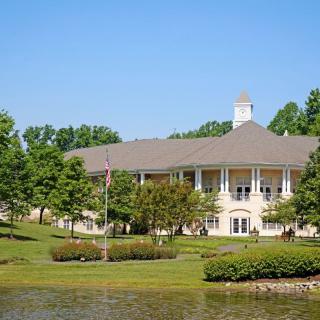 A scenic view of a building surrounded by greenery and a small lake.