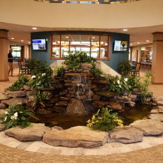 A beautifully designed indoor fountain surrounded by plants in a lobby area.