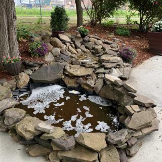 A serene garden pond with cascading rocks and a peaceful atmosphere.