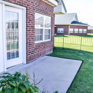 A backyard patio area with a brick exterior and a fenced lawn.