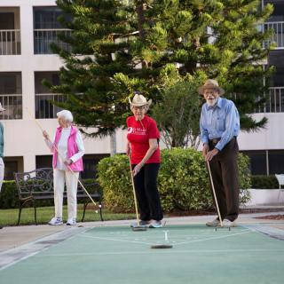 A group of seniors playing shuffleboard outdoors.