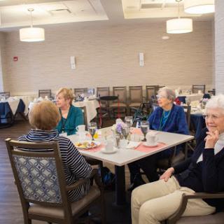 A group of seniors enjoying a lively breakfast discussion in a cozy dining area.