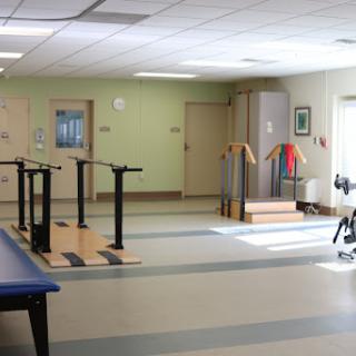 A spacious rehabilitation room equipped with therapy bars and exercise equipment.