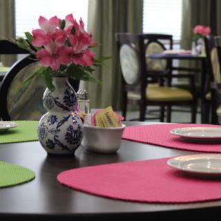 A beautifully arranged dining table with colorful placemats and a floral centerpiece.