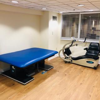 A therapy room featuring an exercise bike and a treatment table.