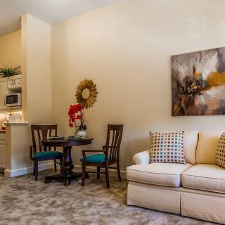 A cozy living room with a sofa, dining set, and wall art.