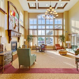 A spacious and well-lit lobby with large windows, elegant furniture, and a chandelier.