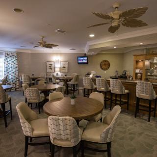A cozy lounge area with round tables, comfortable chairs, and a bar.