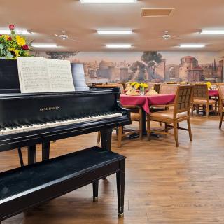 A dining area with a piano and tables set for service.
