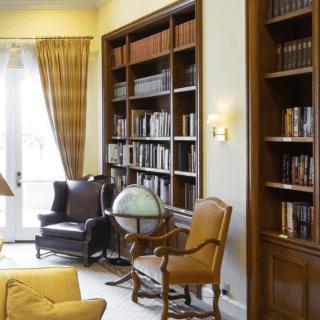 A cozy library with tall bookshelves, a globe, and comfortable chairs.