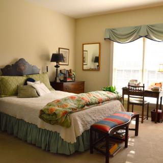 A cozy bedroom with a bed, desk, and window.