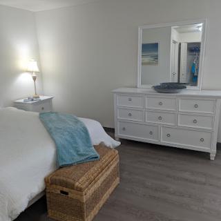 A serene and minimalistic bedroom featuring a comfortable bed, stylish white furniture, and soft decorative elements.