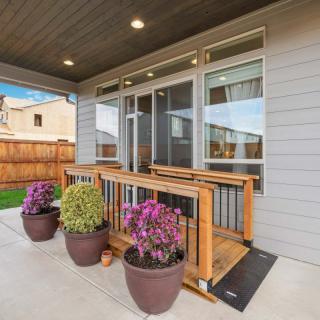 A cozy porch with potted plants and a wooden railing overlooking a backyard.