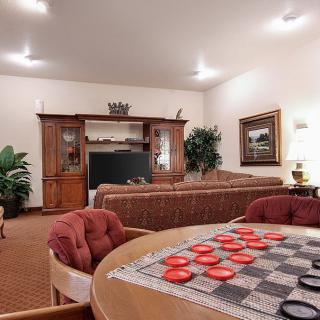 A cozy living room with a checkerboard table and entertainment center.