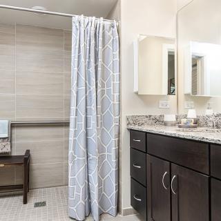 A modern bathroom featuring a shower with a curtain, a sink with dark cabinetry, and a large mirror.