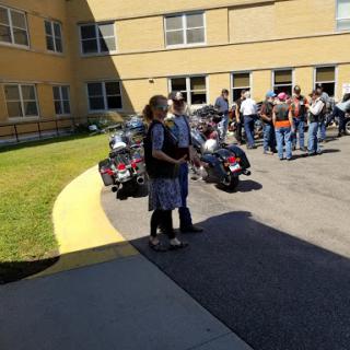 A group of people gathered outside a building, with motorcycles parked nearby.