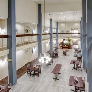 A spacious, modern restaurant interior featuring high ceilings and elegantly arranged dining tables.