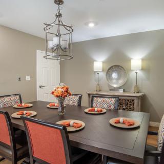 A modern dining room with a large table set for six, featuring stylish chairs and elegant decor.