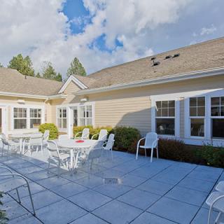 A sunny patio area with outdoor seating and tables surrounded by a building.