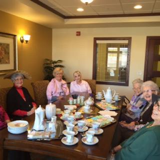 A cheerful tea party with a group of senior women enjoying each other's company.