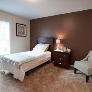 A cozy bedroom with a single bed, nightstand, and armchair.