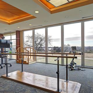 A modern rehabilitation therapy room with exercise equipment and large windows.