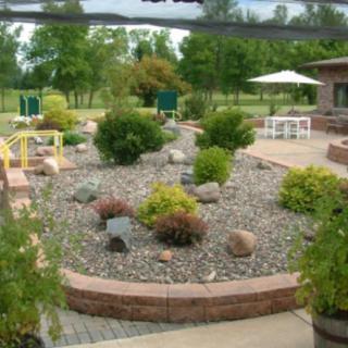 A landscaped garden with rocks and shrubs surrounding a patio area.