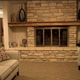 A cozy living room with a stone fireplace and comfortable seating.