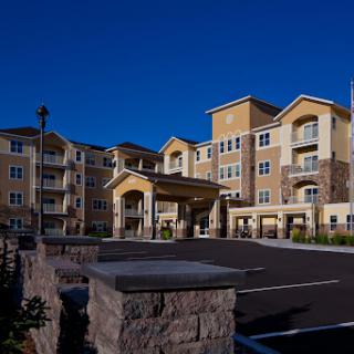 A modern multi-story apartment complex set against a clear blue sky.