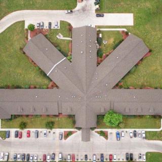 Aerial view of a symmetrical building with surrounding parking area.