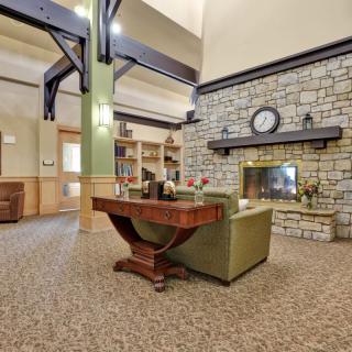 A cozy living room interior with a stone fireplace, comfortable seating, and decorative elements.