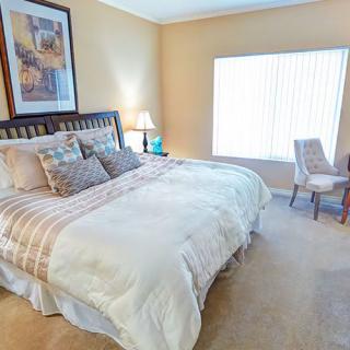 A cozy bedroom with a large bed, stylish decor, and natural lighting.